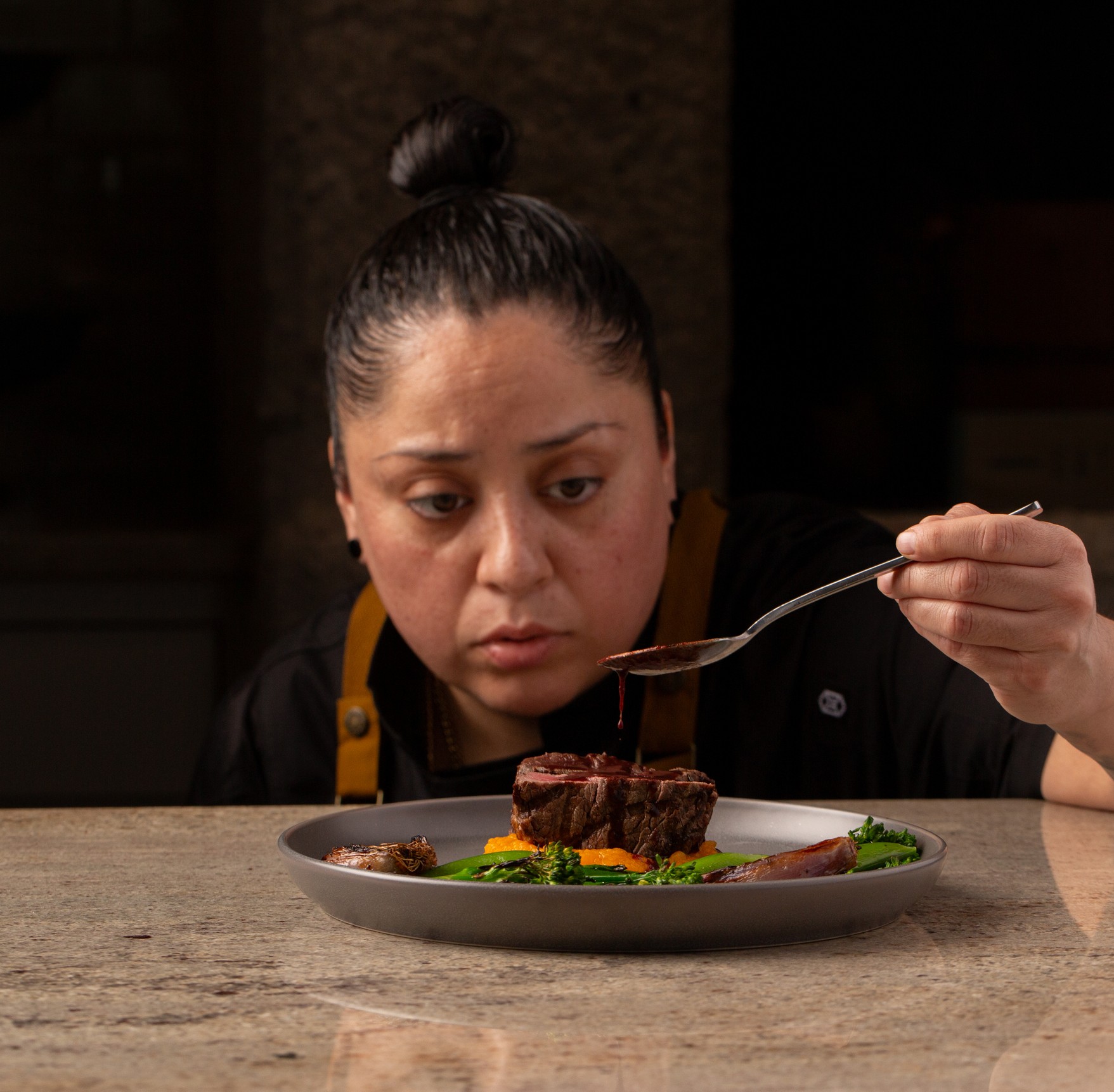 Chef Rosie Sanchez tasting a dish, photographed by Seth Brammer